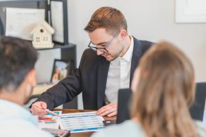 Couple sitting across the desk from a real estate agent who is helping them decide whether to rent or buy a home in Philadelphia