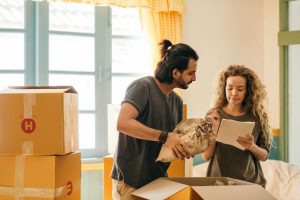 ouple surrounded by cardboard boxes packing for a move